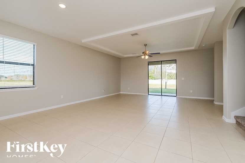 an empty living room with a ceiling fan and a sliding glass door