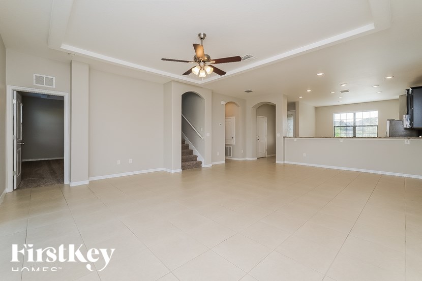 an empty living room and kitchen with a ceiling fan
