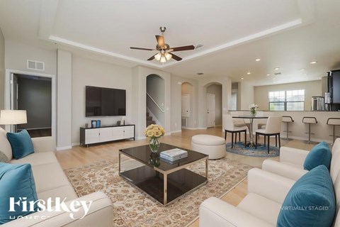 A modern living room with a glass coffee table and a ceiling fan.