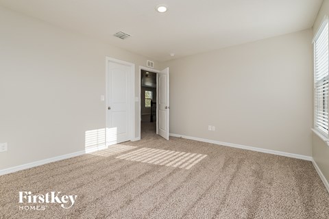 a spacious living room with carpet and a door to the hallway