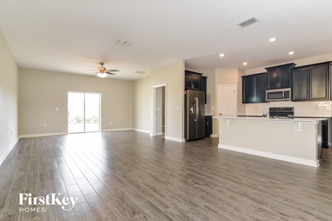 a kitchen and living room with wood flooring and black cabinets