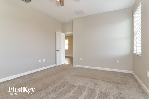 a spacious living room with carpet and a door to a hallway