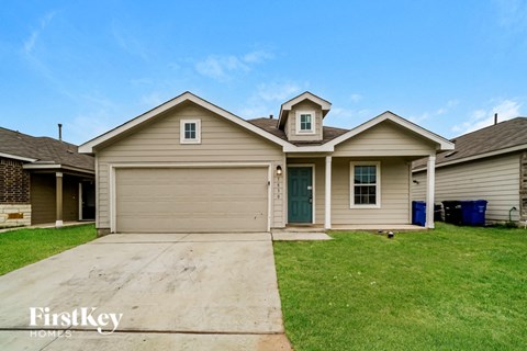a beige house with a green lawn and a driveway