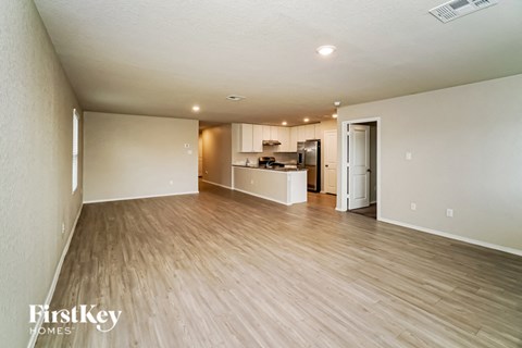 an empty living room and kitchen with wood flooring