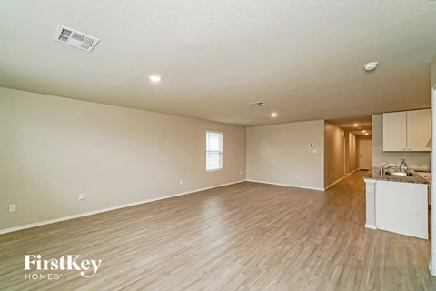 an empty living room and kitchen with wood flooring