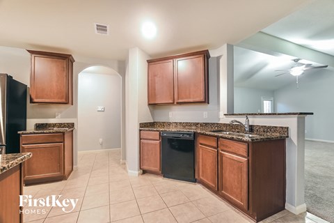 A kitchen with wooden cabinets and a black dishwasher.