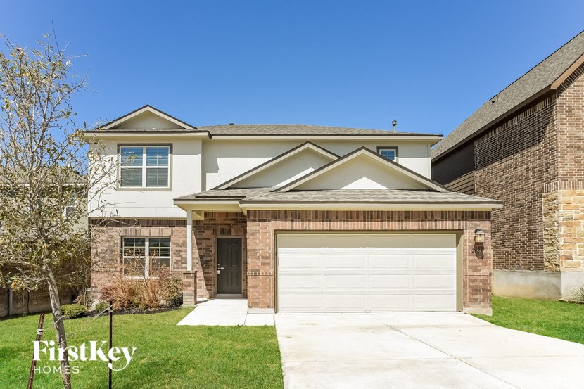 A house with a garage and a tree in front of it.