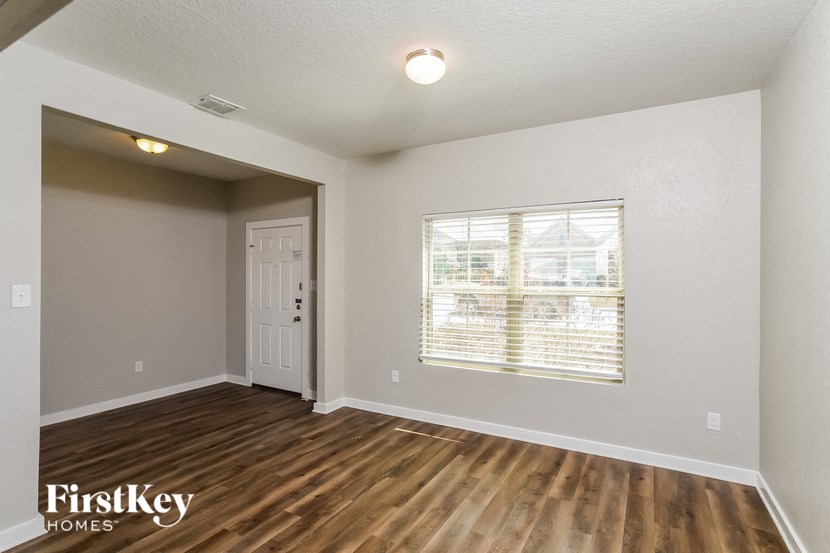 A room with wooden floors and a window with blinds.