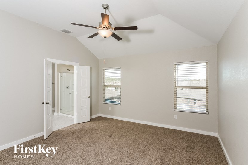 A room with a carpet floor, a ceiling fan, and a window with blinds.