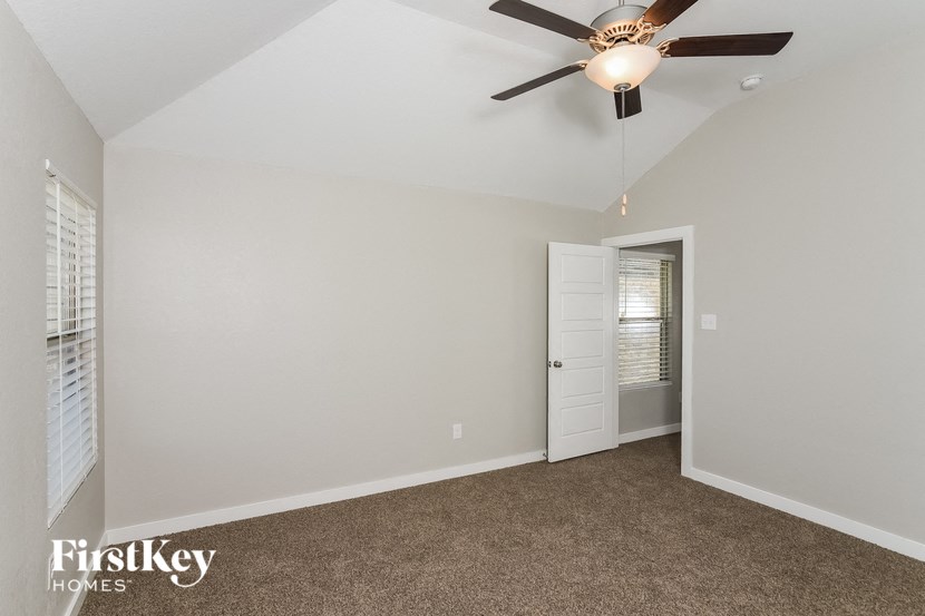A room with a ceiling fan and a door leading to another room.