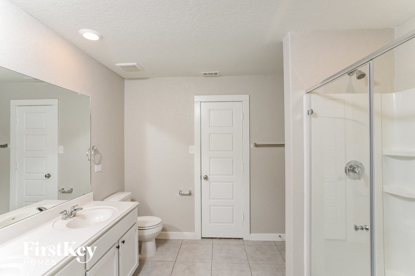 A white bathroom with a toilet, sink, and shower.