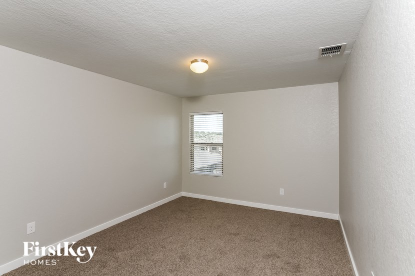 A small, empty room with a window and a carpeted floor.