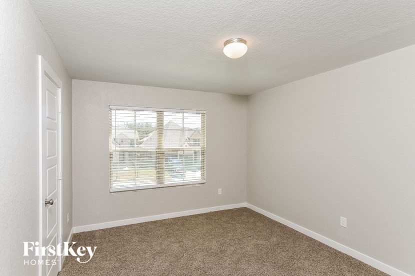 A room with a carpeted floor and a window with blinds.