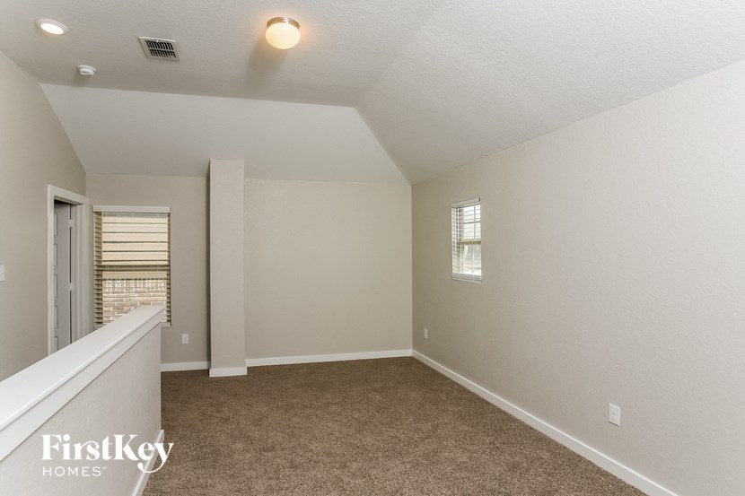 A room with a carpeted floor and a window with blinds.