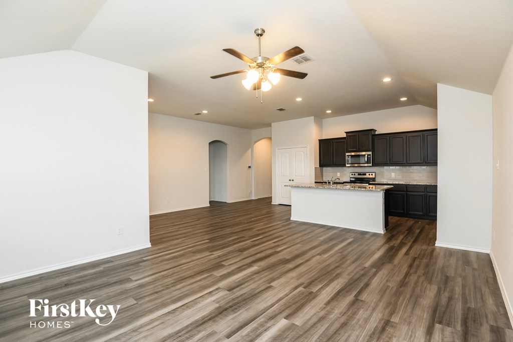 an open kitchen and living room with wood flooring and a ceiling fan