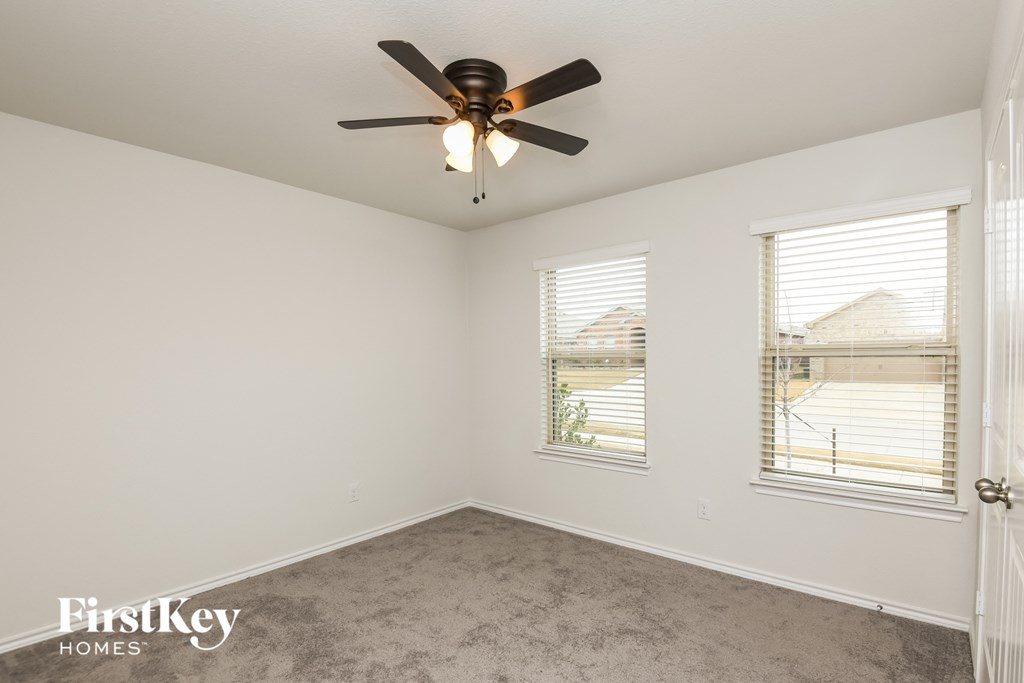 a bedroom with a ceiling fan and two windows