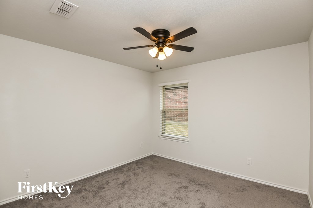 a empty room with a ceiling fan and a window