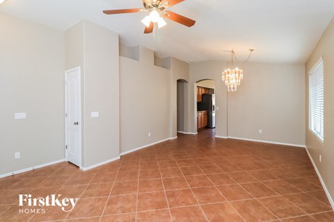 an empty living room with a ceiling fan and a tile floor