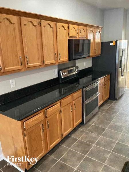 A kitchen with wooden cabinets and black countertops.