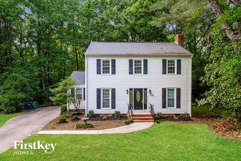 a white house with black shutters and a driveway