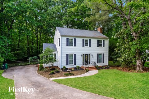 a white house with green trees and a driveway