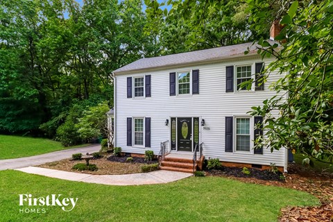 a white house with black shutters and a lawn and trees