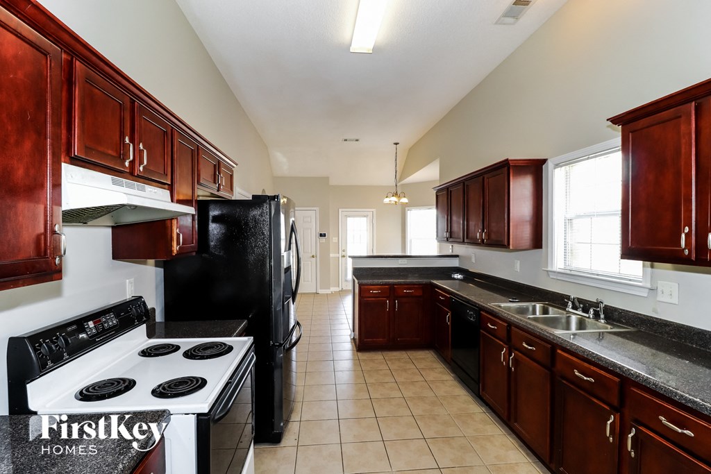 a kitchen with black appliances and brown cabinets and a white stove