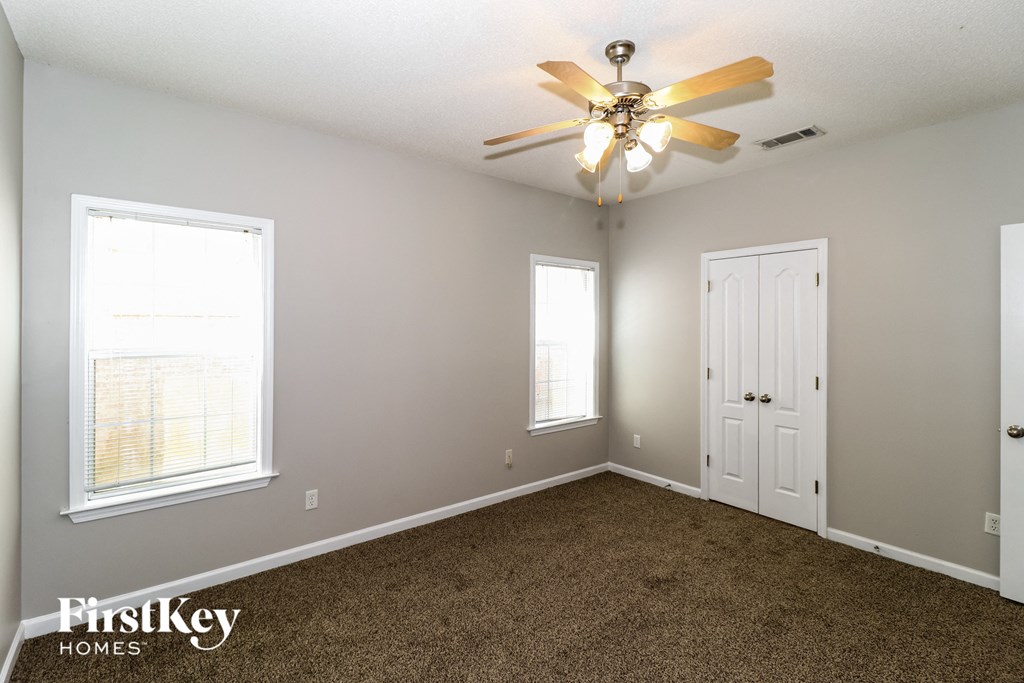 a bedroom with carpet and a ceiling fan and two windows