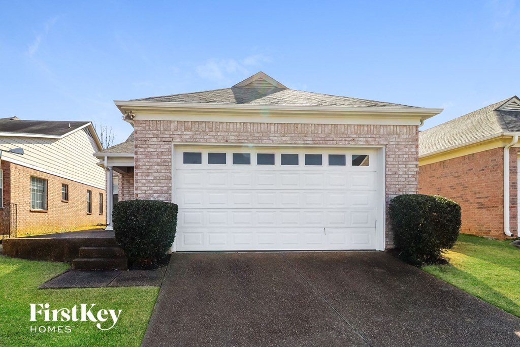 a white garage door in front of a brick house