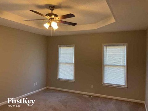 a bedroom with a ceiling fan and two windows