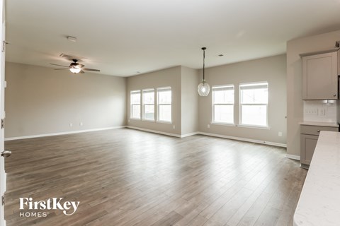 A spacious room with wooden floors and a ceiling fan.