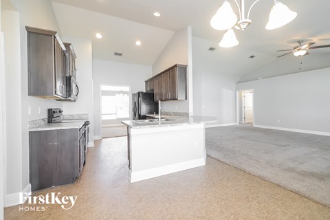a kitchen and living room with a white floor and white cabinets and a white counter