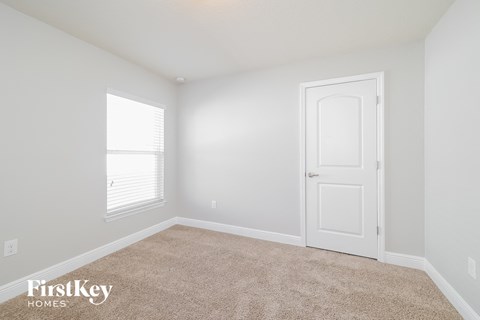 a bedroom with white walls and a white door and carpet