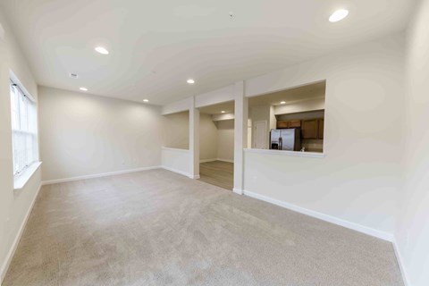 A spacious room with a carpeted floor and a window on the left side.