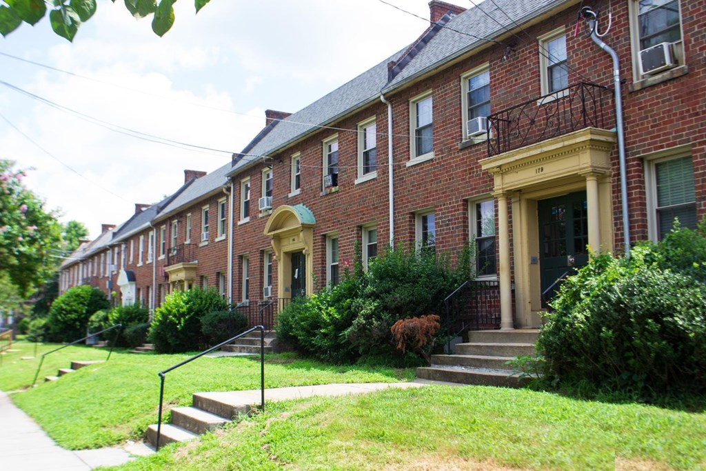 A row of red brick houses with green lawns in front.