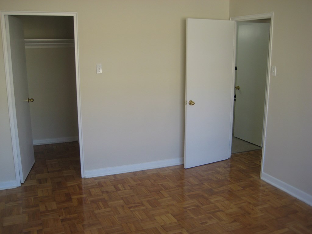 an empty room with a wood floor and two doors