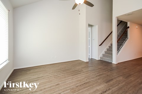 A spacious room with wooden flooring and a staircase.