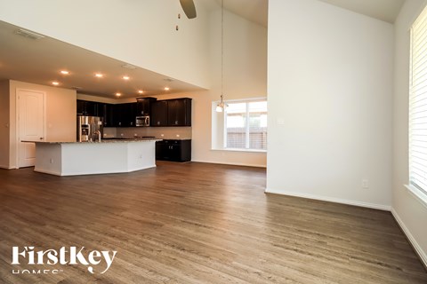 A spacious kitchen and living room with wooden floors and white walls.