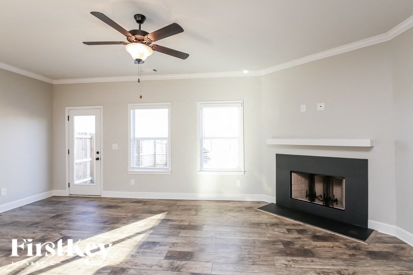 A spacious living room with a fireplace and a ceiling fan.