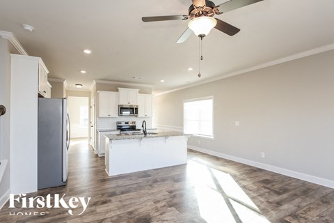 A spacious kitchen with a ceiling fan and wooden flooring.