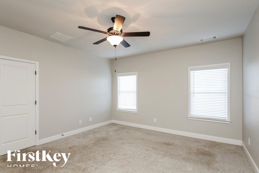 A room with a ceiling fan and two windows.