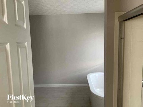 A white bathroom with a tub and a door.