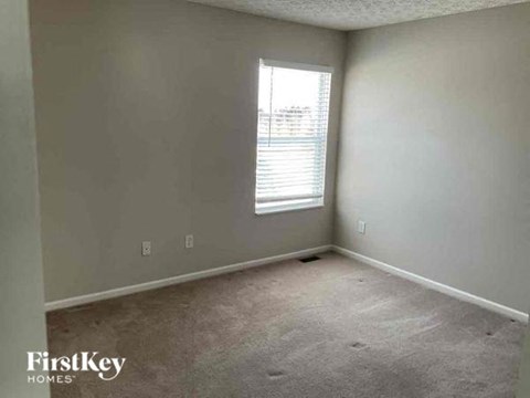 A room with a window and carpeted floor.