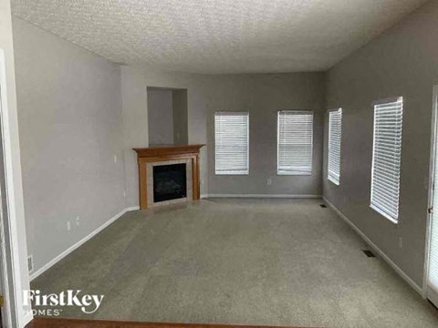 A living room with a fireplace and a window with blinds.