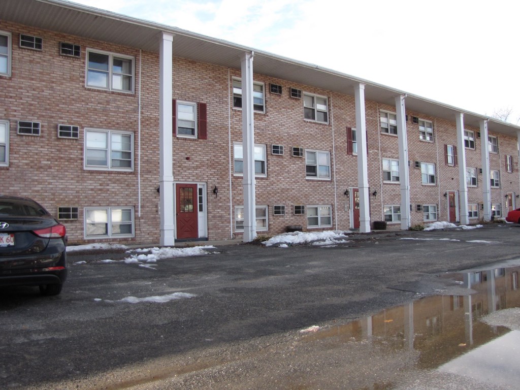 a large brick apartment building with a car parked outside