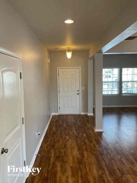 A long hallway with wood floors and white walls.