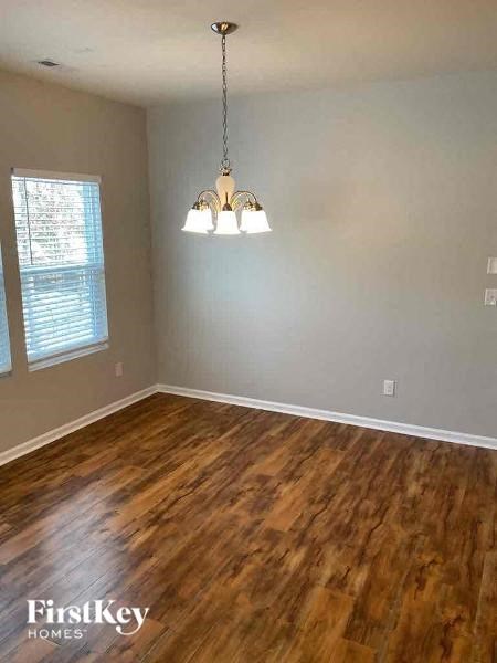 A room with wooden flooring and a chandelier hanging from the ceiling.