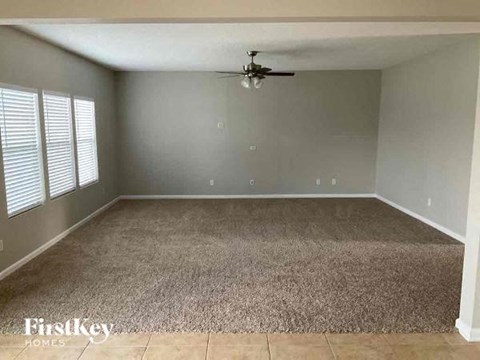 a empty living room with a ceiling fan and a carpet