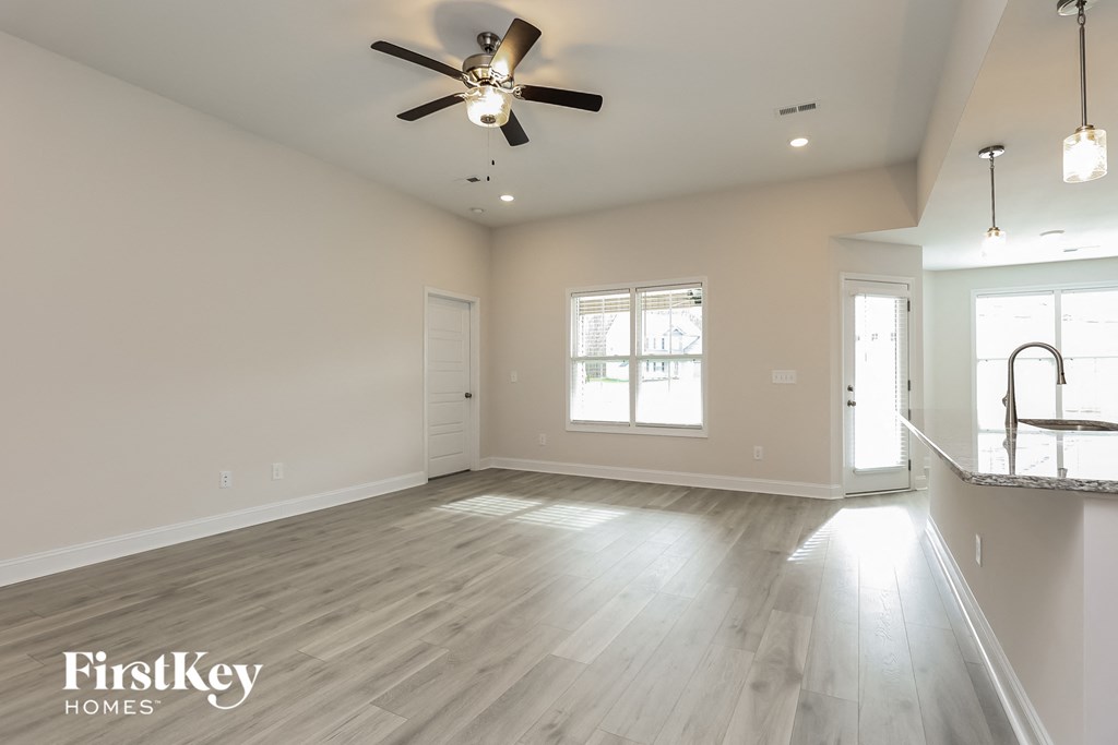 a clean and empty living room with a ceiling fan