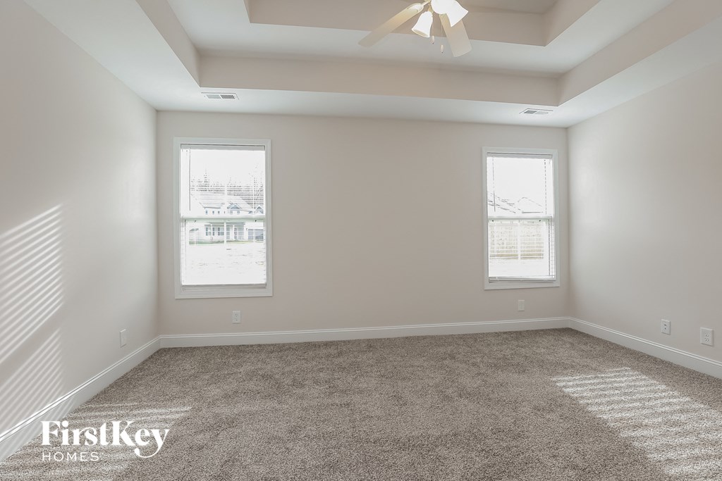 a empty room with two windows and a ceiling fan